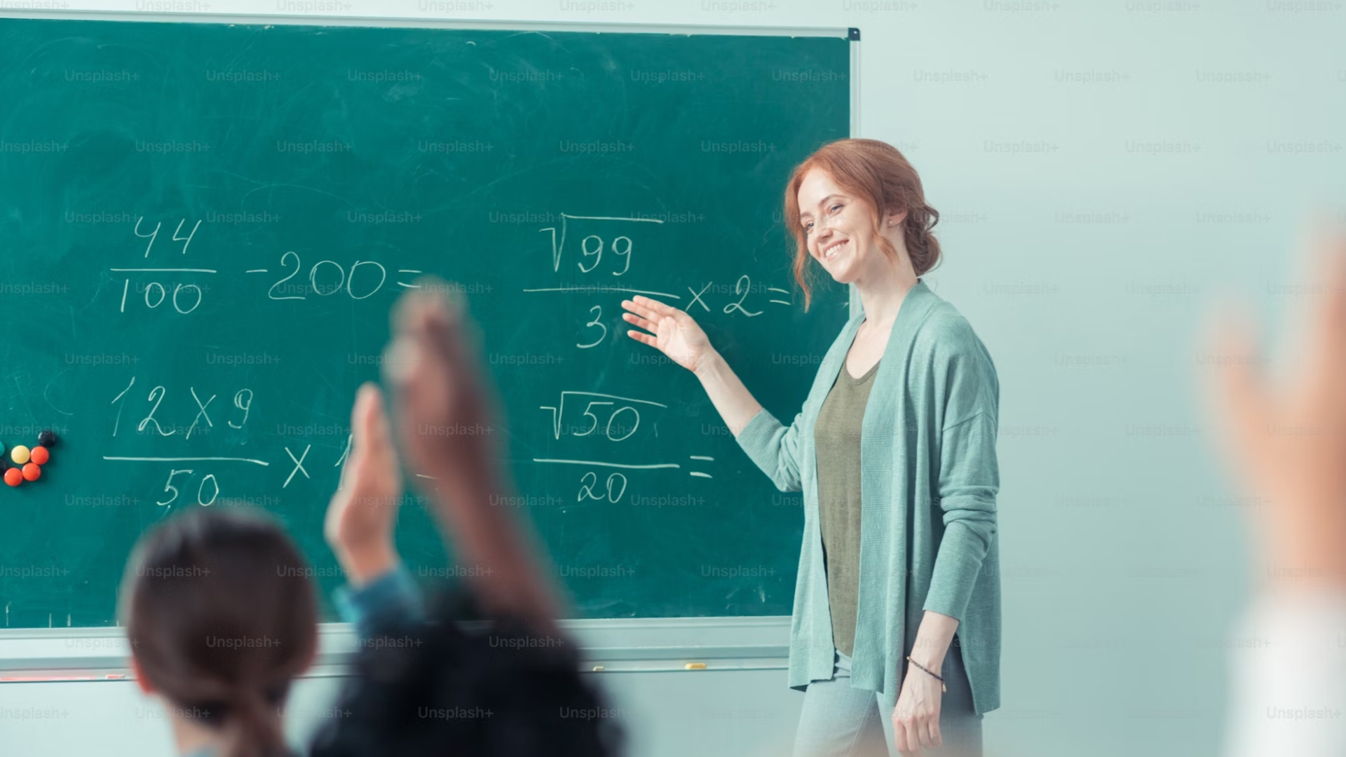 Teacher smiling by a blackboard with math equations on it