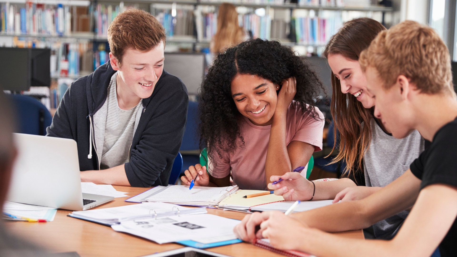 High school students smiling as the work on homework together at a table