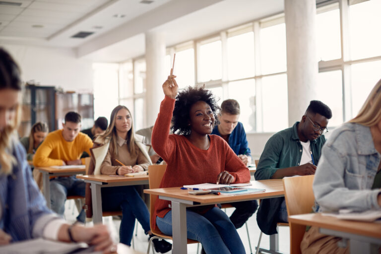 student smiling and raising their hand