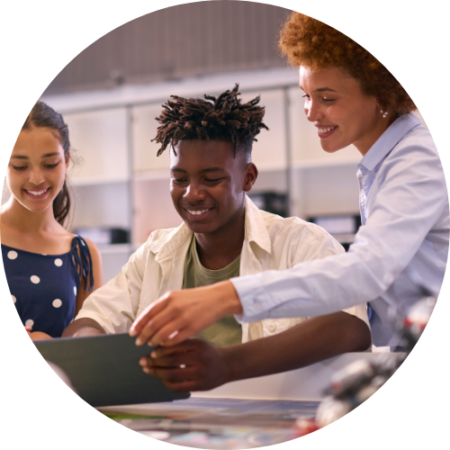 a teacher smiling while helping two students