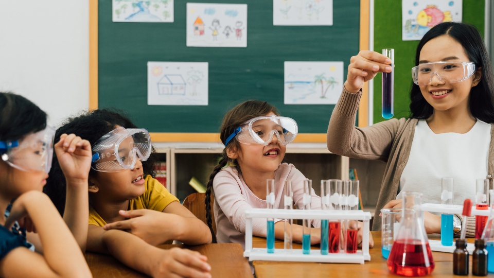 three elementary school kids with their teacher in a science class