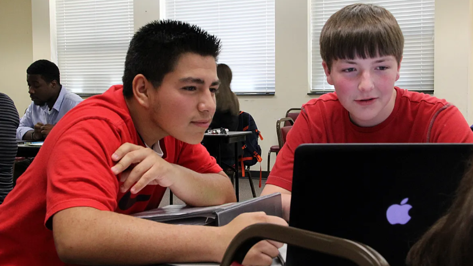 two male students working on a laptop together