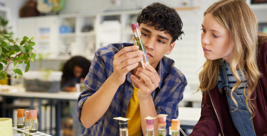 two students examining a vial in a science lab