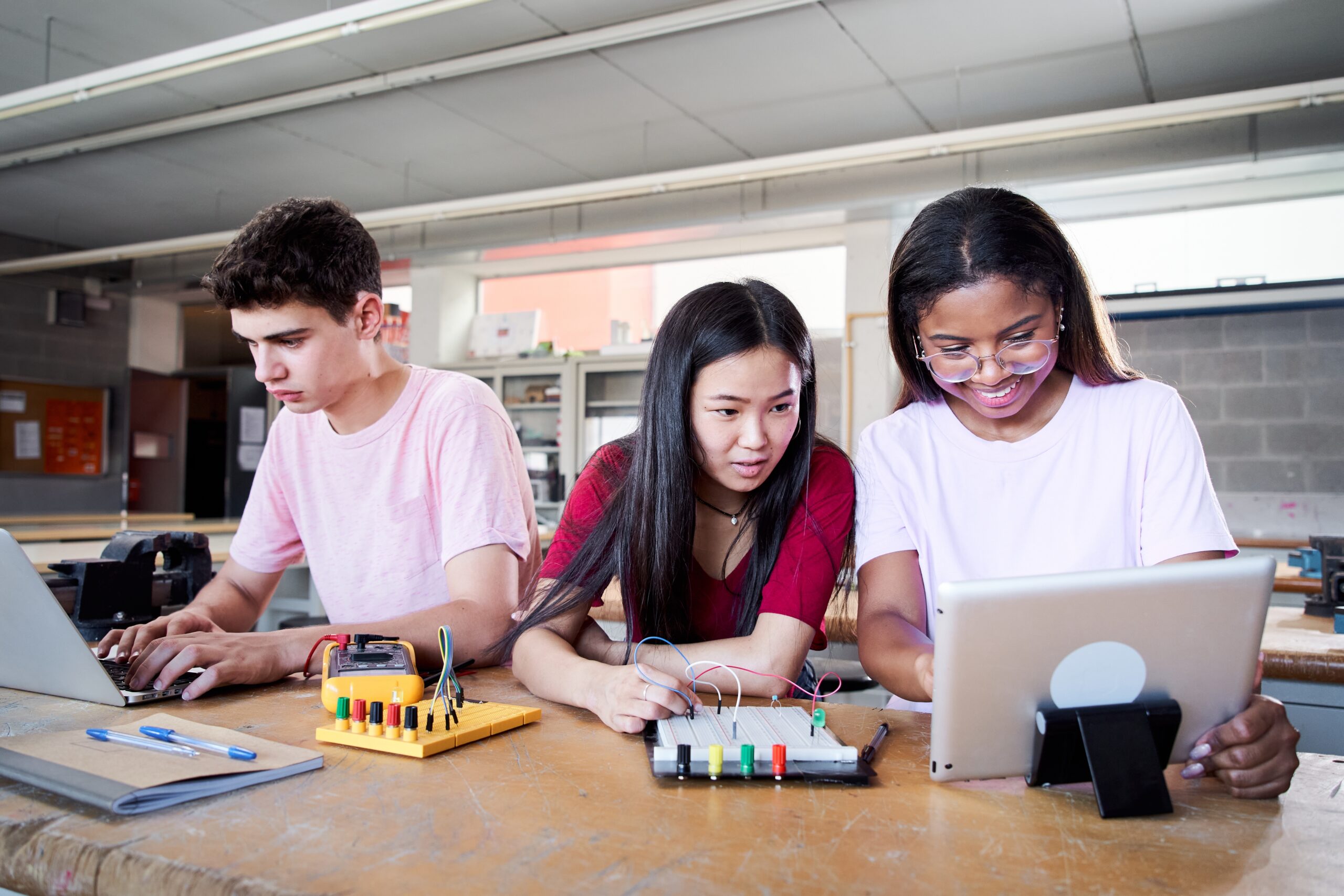 three high school students working on a project in a classroom