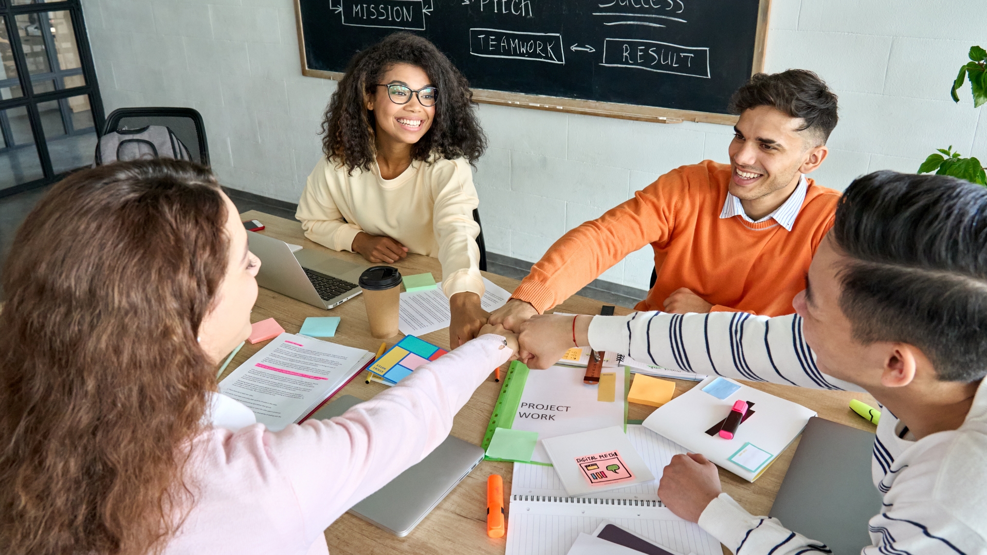 four high school students sitting around a table, working on a group project