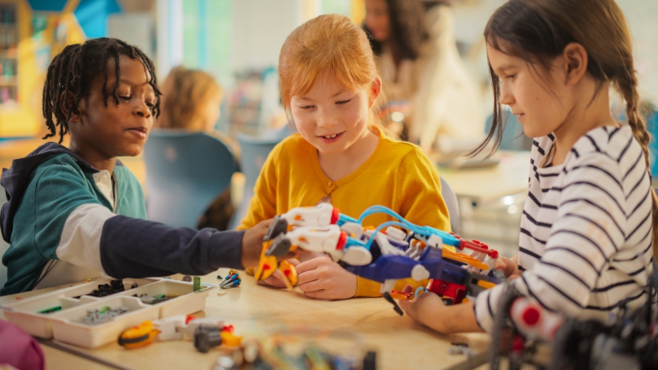 three young elementary age students exploring a STEM toy
