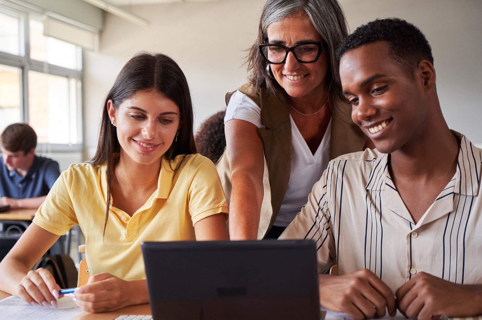 teacher and two students looking at a computer